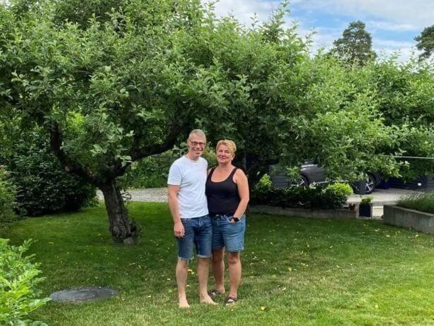 Homeowners stand beneath an apple tree in their backyard after a WaBack backflow valve protected their home in heavy rain